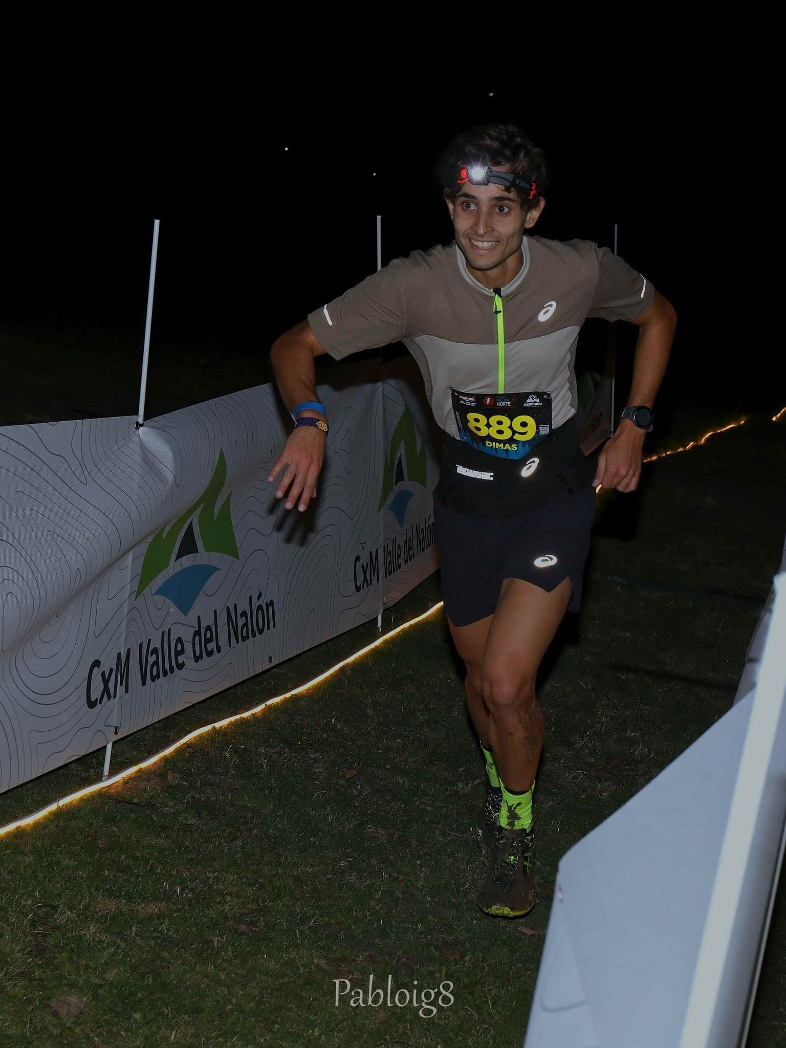 Corredor con linterna frontal en el pasillo iluminado de la carrera nocturna